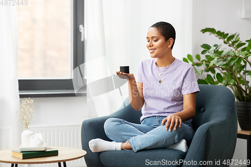 Image of african american woman with smart speaker at home