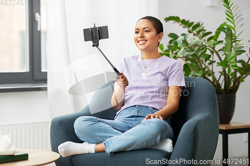 Image of happy african american woman taking selfie at home