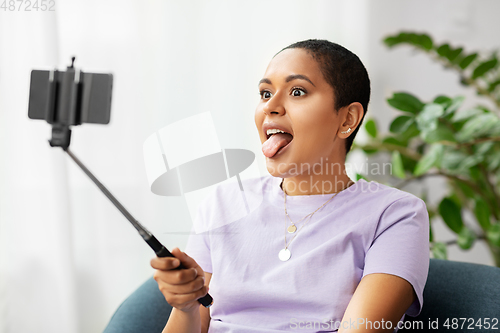 Image of happy african american woman taking selfie at home