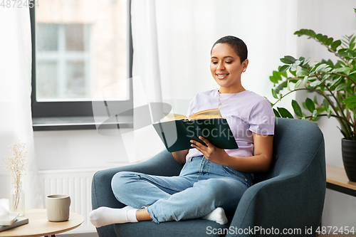 Image of happy african american woman reading book at home