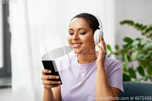 Image of woman with smartphone listening to music at home