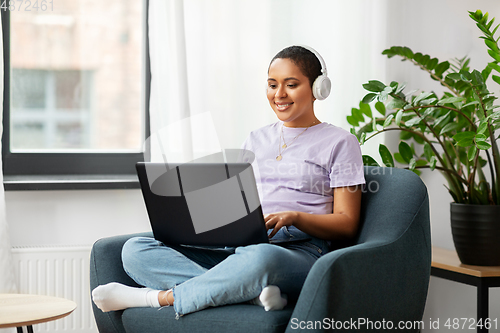 Image of woman with laptop listening to music at home