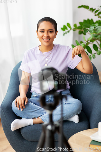 Image of female blogger with camera video blogging at home