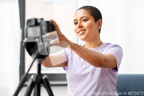 Image of female video blogger adjusting camera at home