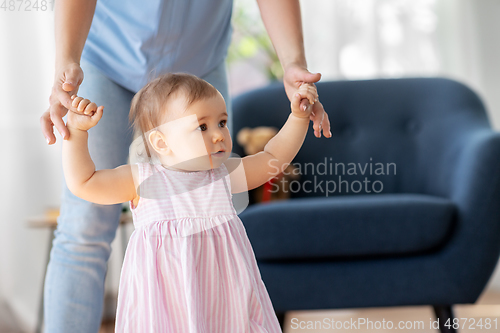 Image of baby girl learning to walk with mother's help