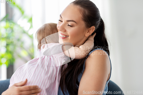 Image of happy mother hugging little baby daughter at home