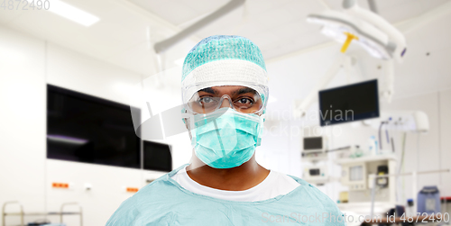 Image of indian male surgeon in mask over operating room