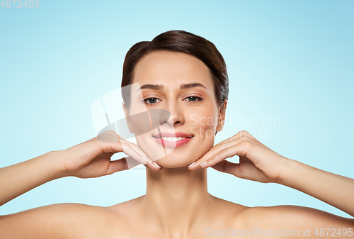 Image of beautiful young woman touching her face and chin