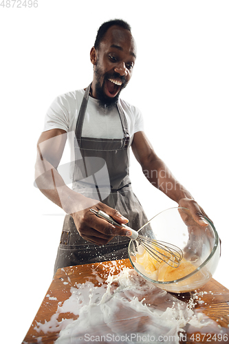 Image of Amazing african-american man preparing unbelievable food with close up action, details and bright emotions, professional cook. Preparing omelet, mixing eggs with splashing milk