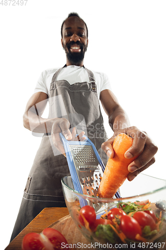 Image of Amazing african-american man preparing unbelievable food with close up action, details and bright emotions, professional cook. Cutting carrot to salad