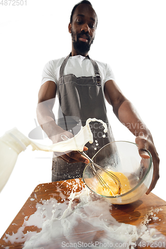 Image of Amazing african-american man preparing unbelievable food with close up action, details and bright emotions, professional cook. Preparing omelet, mixing eggs with splashing milk