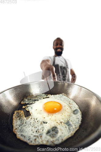 Image of Amazing african-american man preparing unbelievable food with close up action, details and bright emotions, professional cook. Preparing fried eggs