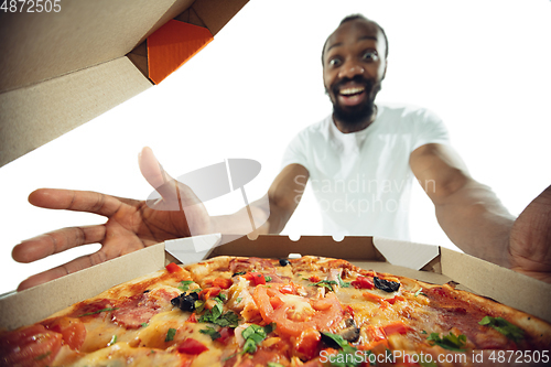 Image of Amazing african-american man preparing unbelievable food with close up action, details and bright emotions, professional cook. View from out the box with pizza