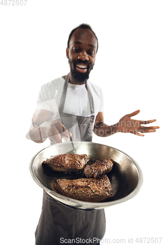 Image of Amazing african-american man preparing unbelievable food with close up action, details and bright emotions, professional cook. Preparing fried meat, steakes