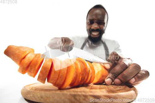 Image of Amazing african-american man preparing unbelievable food with close up action, details and bright emotions, professional cook. Cutting carrot on the fly