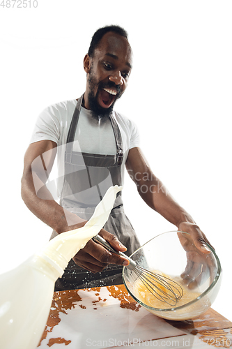 Image of Amazing african-american man preparing unbelievable food with close up action, details and bright emotions, professional cook. Preparing omelet, mixing eggs with splashing milk