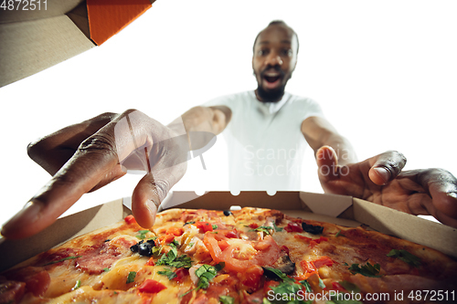 Image of Amazing african-american man preparing unbelievable food with close up action, details and bright emotions, professional cook. View from out the box with pizza