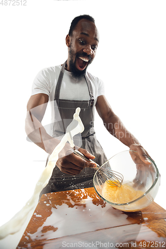 Image of Amazing african-american man preparing unbelievable food with close up action, details and bright emotions, professional cook. Preparing omelet, mixing eggs with splashing milk