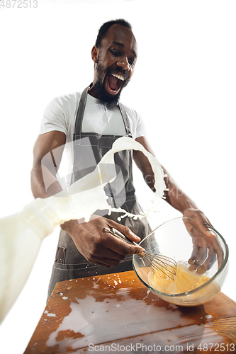 Image of Amazing african-american man preparing unbelievable food with close up action, details and bright emotions, professional cook. Preparing omelet, mixing eggs with splashing milk