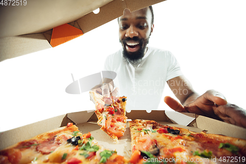 Image of Amazing african-american man preparing unbelievable food with close up action, details and bright emotions, professional cook. View from out the box with pizza
