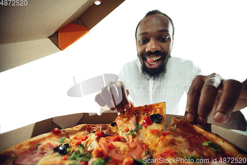 Image of Amazing african-american man preparing unbelievable food with close up action, details and bright emotions, professional cook. View from out the box with pizza