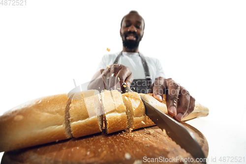 Image of Amazing african-american man preparing unbelievable food with close up action, details and bright emotions, professional cook. Cutting bread