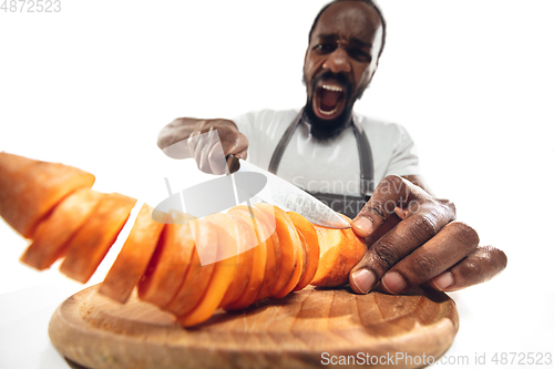 Image of Amazing african-american man preparing unbelievable food with close up action, details and bright emotions, professional cook. Cutting carrot on the fly