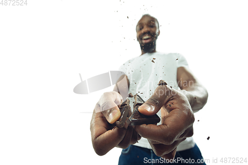 Image of Amazing african-american man preparing unbelievable food with close up action, details and bright emotions, professional cook. Cracking chocolate