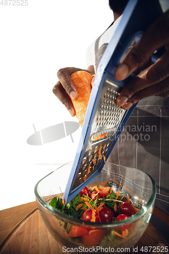 Image of Amazing african-american man preparing unbelievable food with close up action, details and bright emotions, professional cook. Cutting carrot to salad