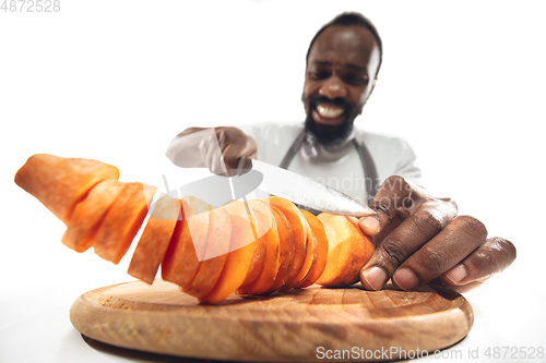 Image of Amazing african-american man preparing unbelievable food with close up action, details and bright emotions, professional cook. Cutting carrot on the fly