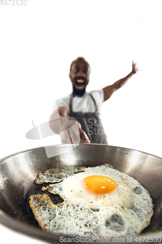 Image of Amazing african-american man preparing unbelievable food with close up action, details and bright emotions, professional cook. Preparing fried eggs