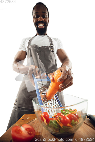 Image of Amazing african-american man preparing unbelievable food with close up action, details and bright emotions, professional cook. Cutting carrot to salad