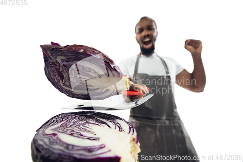 Image of Amazing african-american man preparing unbelievable food with close up action, details and bright emotions, professional cook. Cutting cabbage on the fly