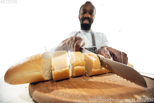 Image of Amazing african-american man preparing unbelievable food with close up action, details and bright emotions, professional cook. Cutting bread