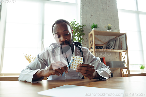 Image of Doctor advising the patient online with laptop. African-american doctor during his videocall, work with patients, explaining recipes for drug.