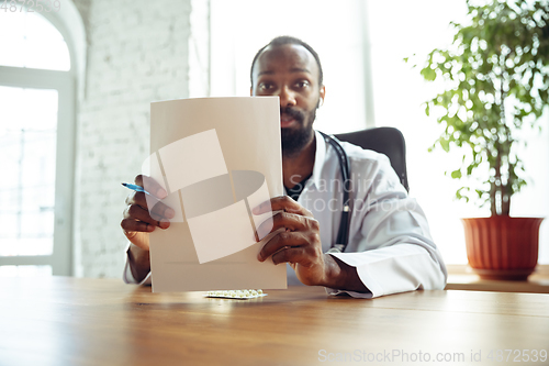 Image of Doctor advising the patient online with laptop. African-american doctor during his videocall, work with patients, explaining recipes for drug.