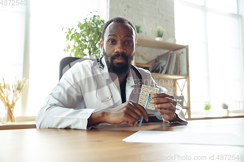 Image of Doctor advising the patient online with laptop. African-american doctor during his videocall, work with patients, explaining recipes for drug.