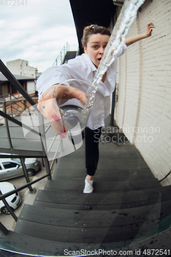 Image of Close up of woman spilling water from glass, action and motion cought in moment, focus on pure splash