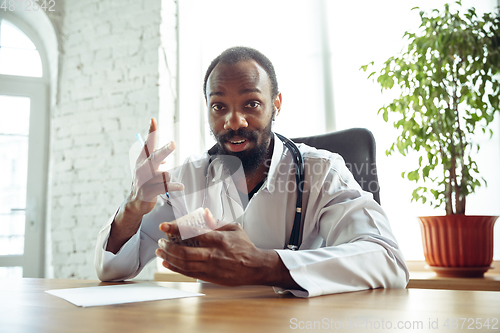 Image of Doctor advising the patient online with laptop. African-american doctor during his videocall, work with patients, explaining recipes for drug.