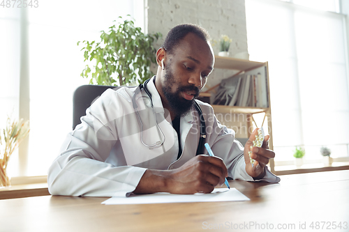 Image of Doctor advising the patient online with laptop. African-american doctor during his videocall, work with patients, explaining recipes for drug.