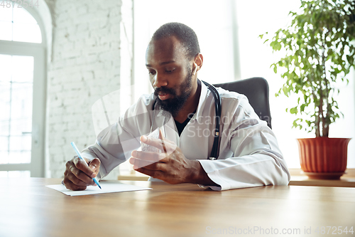 Image of Doctor advising the patient online with laptop. African-american doctor during his videocall, work with patients, explaining recipes for drug.