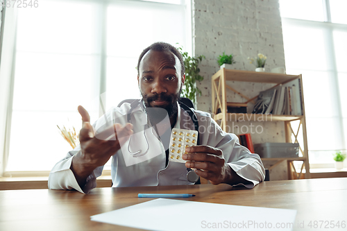 Image of Doctor advising the patient online with laptop. African-american doctor during his videocall, work with patients, explaining recipes for drug.