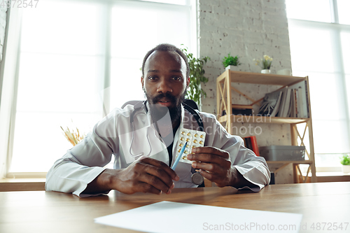 Image of Doctor advising the patient online with laptop. African-american doctor during his videocall, work with patients, explaining recipes for drug.