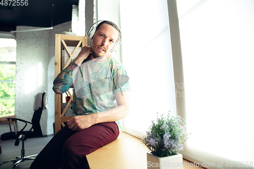 Image of Young man gesturing during a video conference in the living room. Attented listening