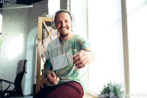 Image of Young man gesturing during a video conference in the living room. Attented listening