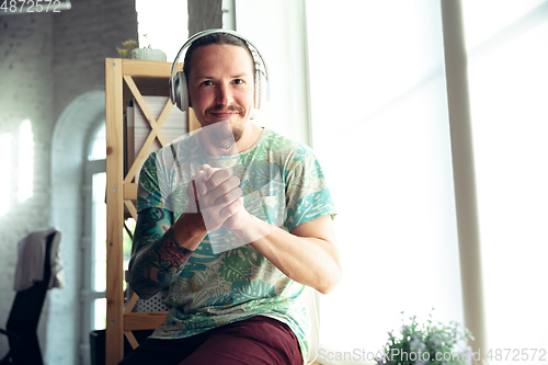 Image of Young man gesturing during a video conference in the living room. Support gesture, smiling