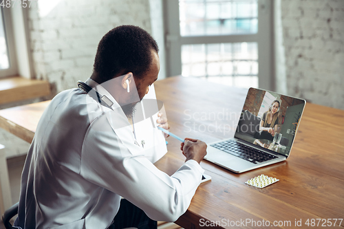 Image of Doctor advising the patient online with laptop. African-american doctor during his videocall, work with patients, explaining recipes for drug.