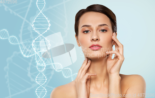 Image of young woman touching her face over dna molecules