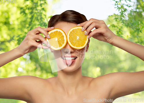 Image of beautiful woman making eye mask of orange slices