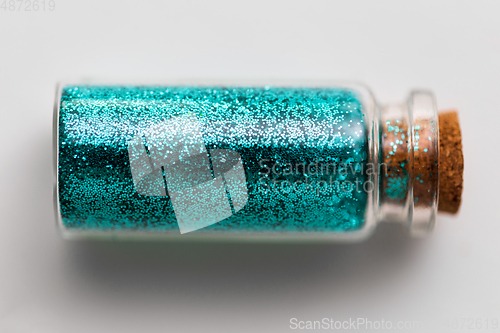 Image of blue glitters in bottle over white background